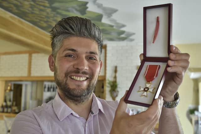 Eye restaurant owner Damian Wawrzyniak with his Polish medal. EMN-180514-231928009