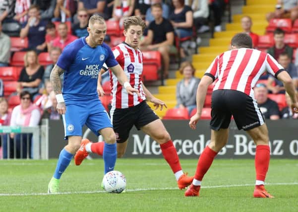 Lincoln's Alex Woodyard (centre) in action against Posh.