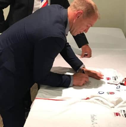 SportsAid chairman Phil Elmer watches on as Neil Back signs some England shirts.