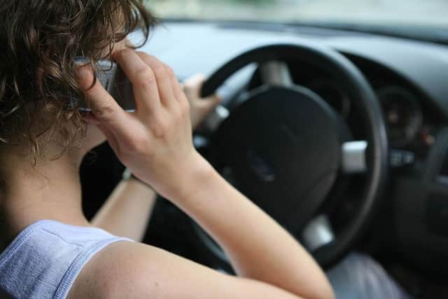 A woman using a mobile phone whilst driving a car.