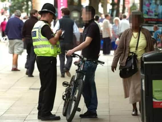 A police officer having stopped a cyclist in Peterborough's Bridge Street