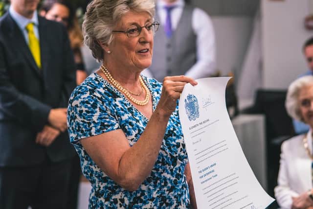 Lady Victoria Leatham holds up the scroll detailing the Queen's Award.