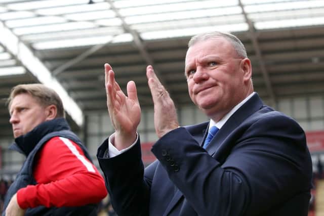 Posh boss Steve Evans applauds the club's fans.
