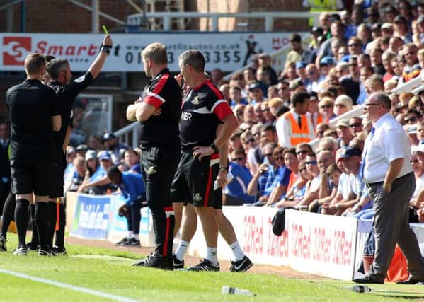 Match referee Darren Bond brandishes a yellow card in the direction of the Posh bench during the draw against Doncaster. Photo: Joe Dent/theposh.com.