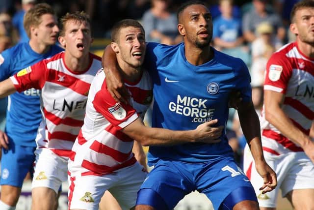 Posh centre-back Rhys Bennett gets to grips with Tommy Rowe of Doncaster.