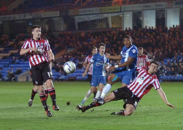 Posh tar Britt Assombalonga is tackled by Harry Maguire of Sheffield United.