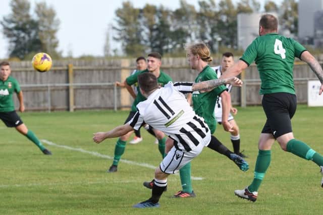 Matthew Barber (stripes) of Peterborough Northern Star has a shot deflected home to make it 1-1 against Sleaford Town. Photo: Chantelle McDonald. @cmcdphotos.