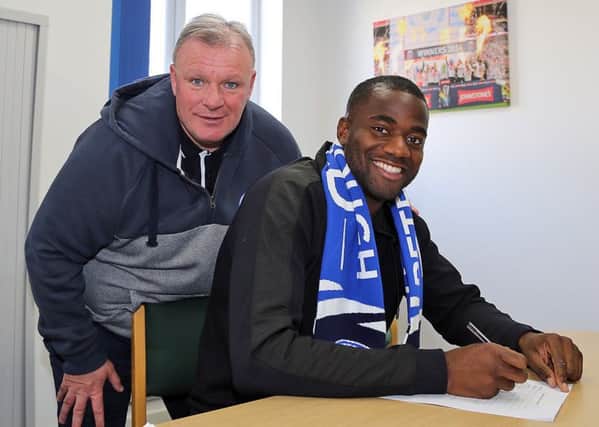 Sebastian Bassong signs for Posh watched by manager Steve Evans. Picture: Joe Dent