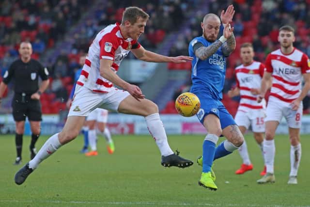 Marcus Maddison of Peterborough United challenges for the ball with Tom Anderson of Doncaster Rovers. Photo: Joe Dent/theposh.com.