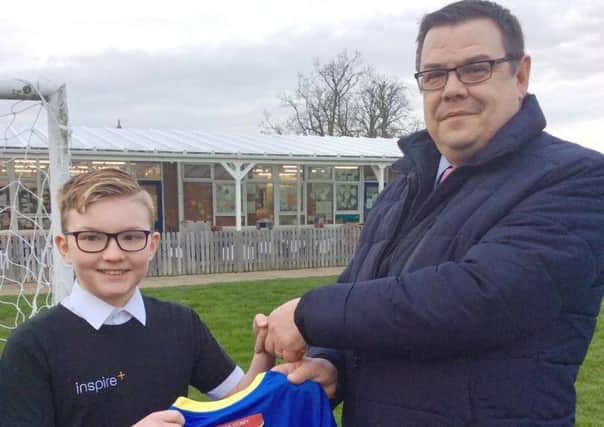 Archie Starsmore, one of the schools Bronze Sports Ambassadors, receives the new sports kit from Julian Welch of Barker Storey Matthews.