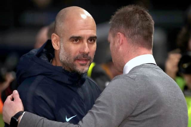 Manchester City manager Pep Guardiola embraces Newport boss Michael Flynn.