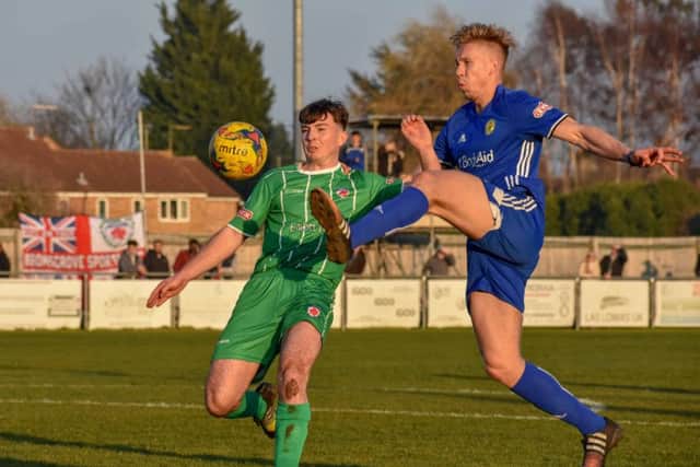 Jim Stevenson (blue) tries to win the ball for Peterborough Sports against Bromsgrove Sporting. Photo: James Richardson.