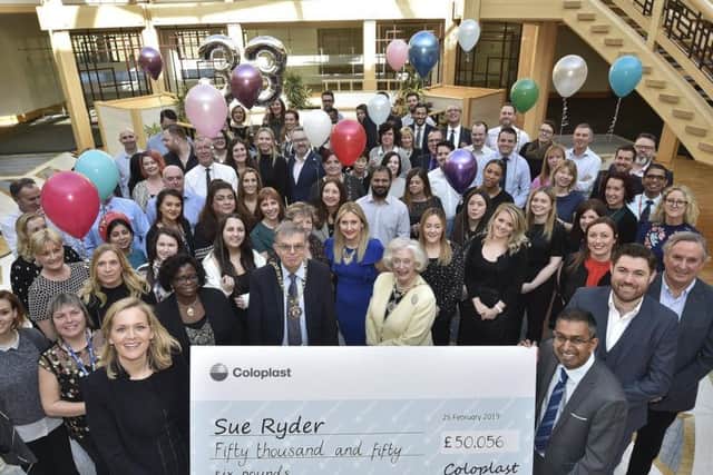 Coloplast country manager Annemarie van Neck present a cheque for 50,056 to Nilesh Patel, of Sue Ryder Thorpe Hall, in Peterborough, watched by Coloplast staff.
