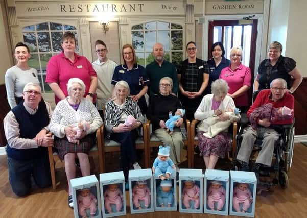 Residents and their families with staff from Cedar Falls care home after John Lewis & Partners in Peterborough donated 14 sensory dolls for residents living with dementia