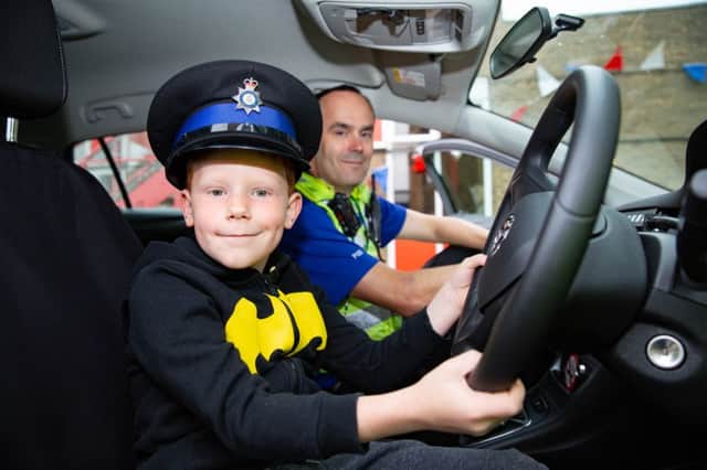 Stanley Snelling (7) tries out a police hat and car for size