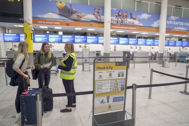 Katie O' Mara (left) and Maddison Millar (centre) talk to a government member of staff in front of empty Thomas Cook check-in desks at Gatwick Airport in Sussex. Photo: Steve Parsons/PA Wire