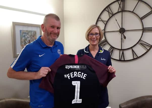 Ian Gow with Sue Ryder nurse Susan Shackleton holding the football top he has had especially printed for his Peterborough United mascot appearance