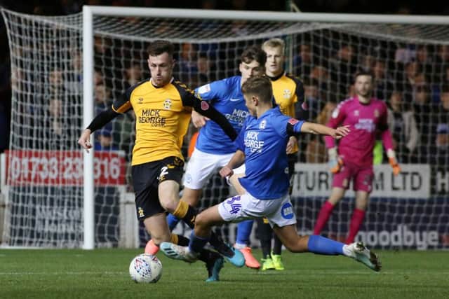 Posh debutant Archie Jones slides in for a tackle on Cambridge United's Paul Lewis. Photo: Joe Dent/theposh.com.