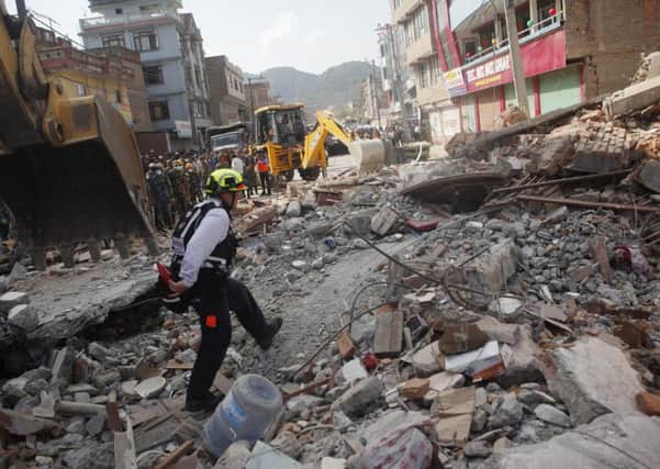 A rescue worker from USAID inspects the site of a building that collapsed in an earthquake in Kathmandu, Nepal, Tuesday, May 12, 2015. A major earthquake has hit Nepal near the Chinese border between the capital of Kathmandu and Mount Everest less than three weeks after the country was devastated by a quake. (AP Photo/Niranjan Shrestha)