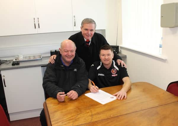 Graham Drury (right) signs a new contract with Stamford AFC watched by secretary Phil Bee (left) and chairman Bob Feetham.