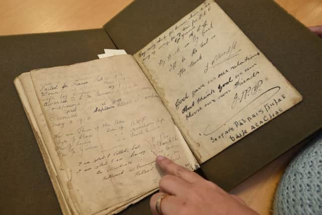 Joy Coster looking at the army records from the old East Station during the war where her father wrote a message EMN-161201-172311009