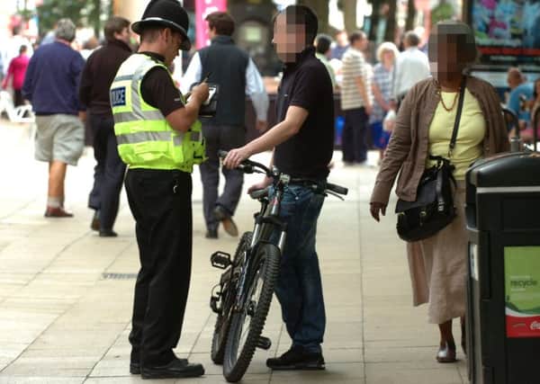 A cyclist is booked by a police officer for riding along Bridge Street during a campaign to reduce the number of cyclists ignoring no cycling signs ENGEMN00120110729165641