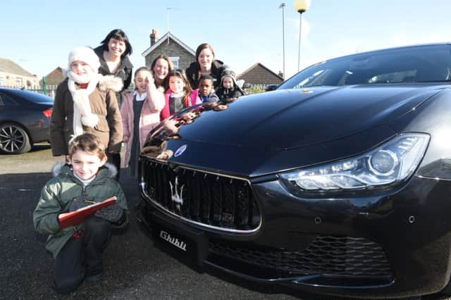 Teacher Helen Veneziguo and head teacher Sarah Levy with Monique Almond from Marshall Maserati and Year 2 children from Old Fletton primary school Supercar club looking at a Maserati
