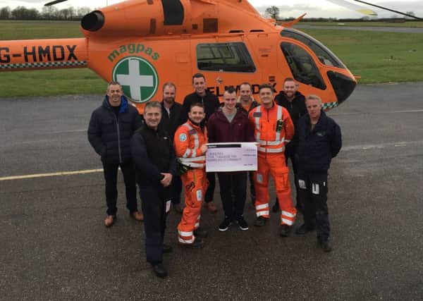 Adam Brooker (centre) and his cycling team mates with Magpas Doctor Chris Adcock (centre right) and Paramedic Simon Standen (centre left) delivering the cheque at