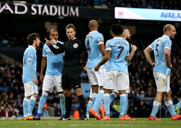 Referee Martin Clattenburg is surrounded by Manchester City players after making an awful penalty decision.