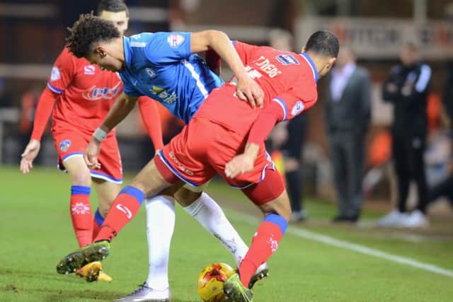 Posh striker Lee Angol tries to squeeze between two Oldham defenders. Photo: David Lowndes.