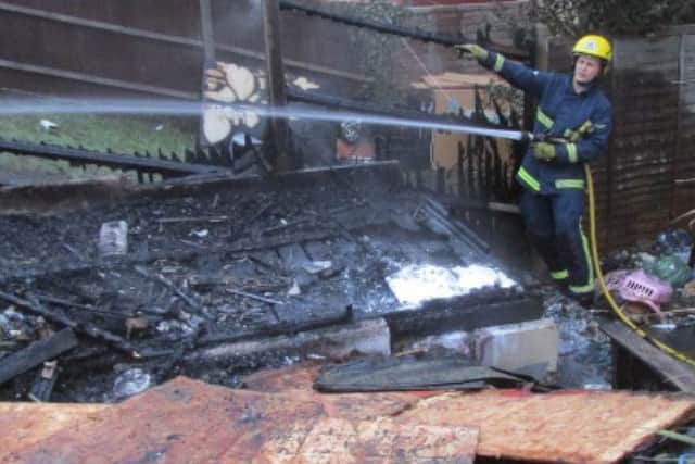 Fire crews dampen down the remains of the garden shed