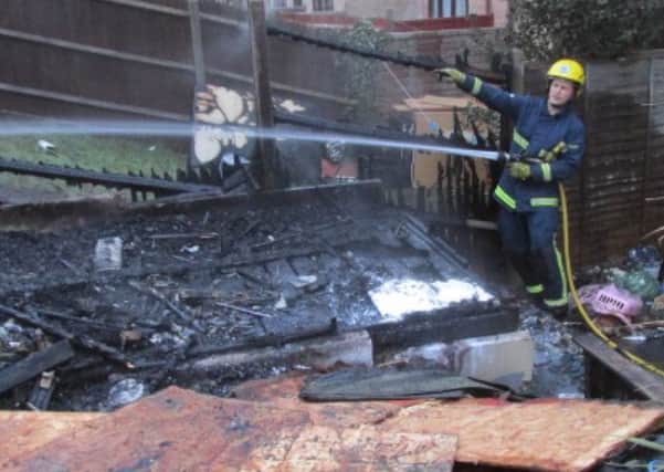Fire crews dampen down the remains of the garden shed