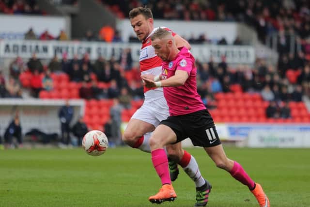 Posh star Marcus Maddison holds off Doncaster's Andy Butler. Photo: Joe Dent/theposh.com.