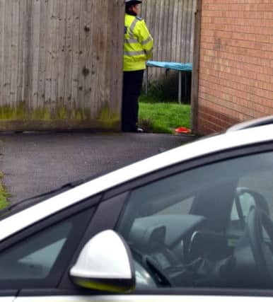 A police officer guards the back of the property.