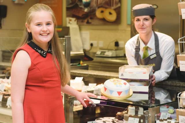 PIC BY GEORGI MABEE/ CATERS NEWS - (PICTURED: CATERS NEWS - (PICTURED: Tilly Chisholm, age nine, pictured at the patisserie section of Waitrose, Stamford, with customer service assistant Abbie Babb. Tilly has won a cake design competition run by Waitrose to celebrate Her Majesty the Queens 90th Birthday.) - EMN-160418-091426001