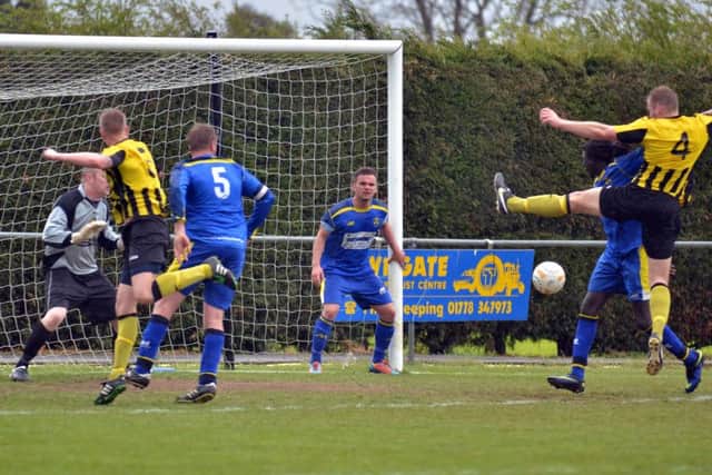 Ollie Pinner (4) of Holbeach stretches to try and make contact with a set-piece in the United Counties League Cup Final against Peterborough Sports. Photo: Tim Wilson.