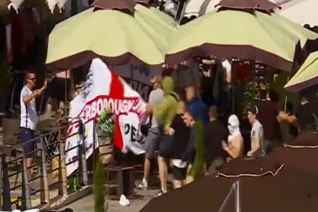 The Peterborough United flag being ripped down by Russian fans. Credit: BBC