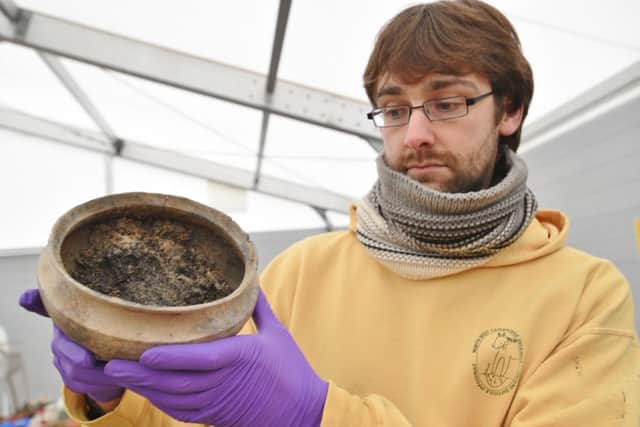 Bronze Age village dig at Whittlesey brick pits at Must Farm Quarry, Funtham's Lane. Chris Wakefield with pot containing Bronze Age food EMN-161101-180905009