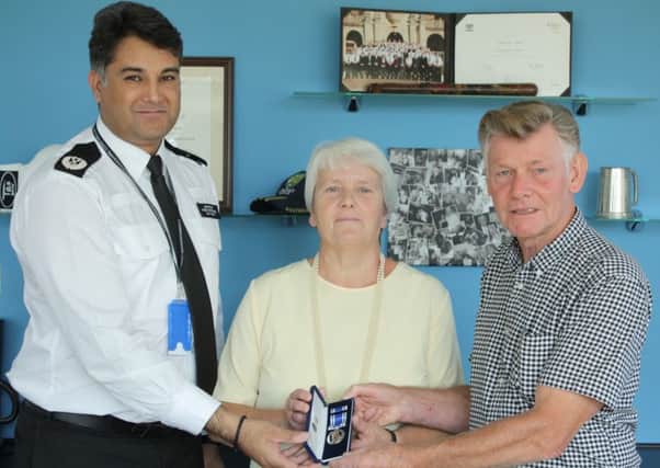 Paul and his wife Christine presented with the medal by Assistant Chief Constable Nav Malik