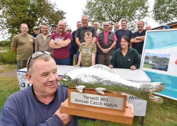 Howard Jones (event organiser) with the trophy for the winner  of the Yarwell Mill angling competition watched by entrants EMN-160820-181127009