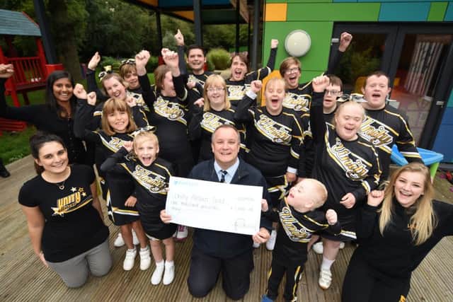 Unity All Stars Gold cheerleaders group receive £1,00 cheque from Mick George key account manager Andrew Goode from the Skip of Gold award EMN-160921-083412009