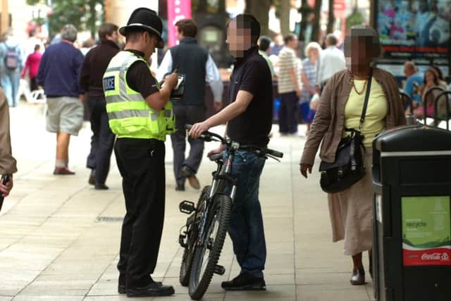 A cyclist is booked by a Police officer for riding along Bridge street during a campaign to reduce the number of cyclists ignoring no cycling signs ENGEMN00120110729165641