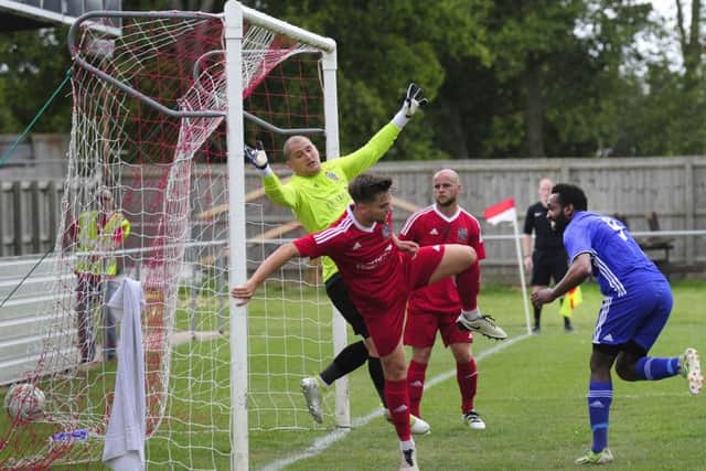 Peterborough Sports' striker Avelino Vieira (blue) scores at Wisbech in the FA Cup.