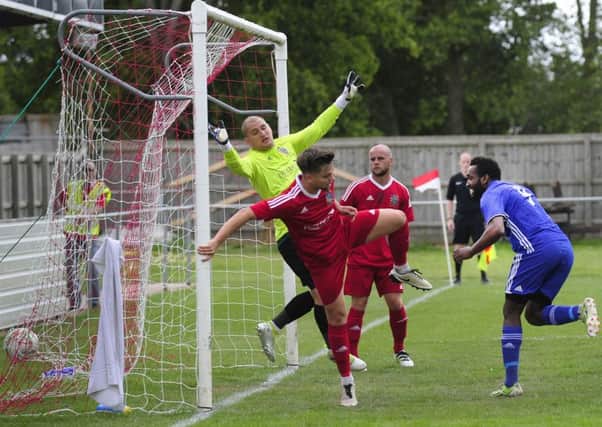 Peterborough Sports' striker Avelino Vieira (blue) scores at Wisbech in the FA Cup.