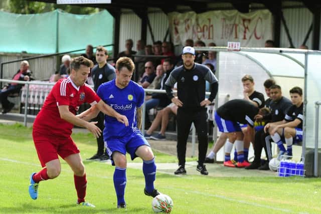 Josh Moreman (blue) in action for Peterborough Sports against Wisbech in an FA Cup tie. Sports manager Jimmy Dean is hovering in the background.