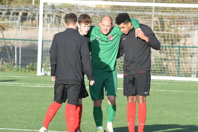 Pinchbeck United goalkeeper Ricky Lovelace limps off early in the game at AFC Stanground Sports. Photo: David Lowndes.