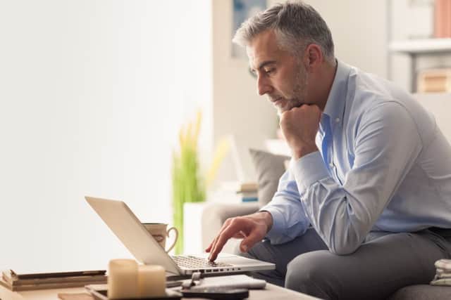Businessman at home sitting on the sofa and working with his laptop, lifestyle and business concept