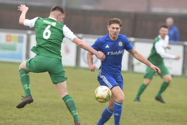 Mark Jones of Peterborough Sports (blue) has his eye on the ball in the FA Vase toe against Biggleswade. Photo: David Lowndes.