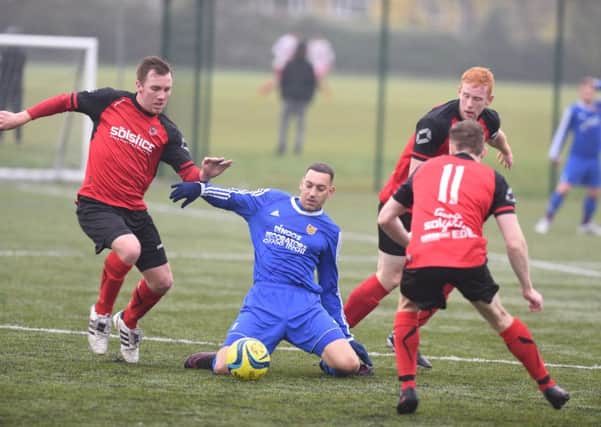 Chris Brown of AFC Stanground Sports is surrounded by Netherton players Ash Jackson (left), Herbie Panting (right) and Tom Randall (11). Photo: Davod Lowndes.