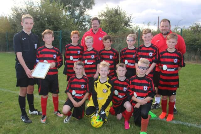 Park Farm Pumas Under 11s are pictured receiving on behalf of their club a framed certificate awarded by the Peterborough Referees Association for outstanding hospitality and attitude to match officials. Making the presentation is Peterborough RA member George Owens. Picture: RWT Photography